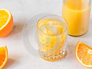 Fresh orange juice with ice cubes in a glass on a table.