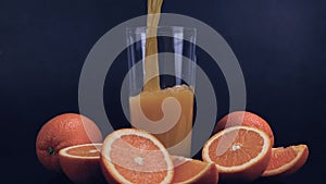 Fresh orange juice poured into the glass on black background