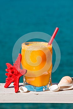 Fresh orange juice on the sea background.