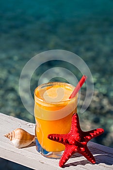 Fresh orange juice on the sea background.