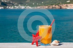 Fresh orange juice on the seaside background.