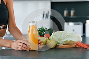 With fresh orange juice. Young european woman is indoors at kitchen indoors with healthy food