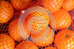 Fresh orange oranges in plastic netting