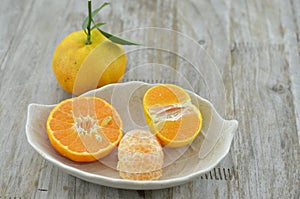 Fresh orange peeled and cut half n plate on wooden background