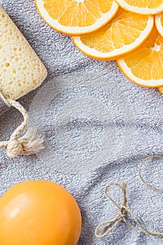 Background for bathing theme: the orange soap, the slices of orange and the bath sponge on the towel