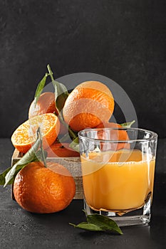 Fresh orange tangerines with green leaves and juice glass