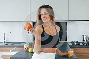 Fresh orange. Young european woman is indoors at kitchen indoors with healthy food
