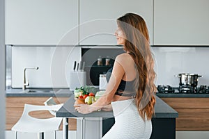 Fresh orange. Young european woman is indoors at kitchen indoors with healthy food