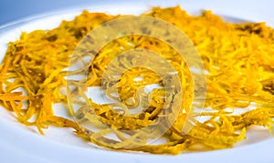 Fresh orange zest on a white plate. Raw citrus zest, grated orange peel, fresh zest on a white background