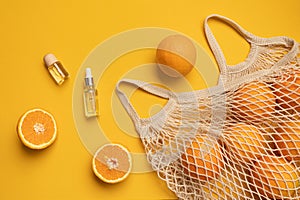 Fresh oranges in a eco bag. Cutted citrus fruit for healthly food. A bottle of essential oils.
