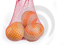 Fresh Oranges in a  Plastic Mesh Sack on a  White Background