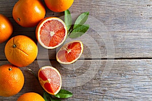 Fresh oranges with slices and leaves on wooden background.