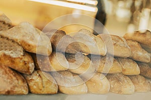 Fresh organic bread on shelves stand of shop, bakery. Freshly baked bread loaves at window of store. Street showcase