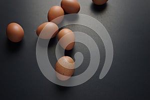 Fresh organic brown eggs with beautiful speckled, freckles on eggshell surface flat lay on black dark background.