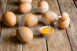 Fresh organic brown eggs scattered on wood table, cracked shells, open yolk