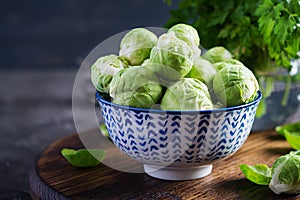 Fresh organic brussels sprouts in a bowl on a dark background.