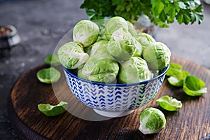 Fresh organic brussels sprouts in a bowl on a dark background.