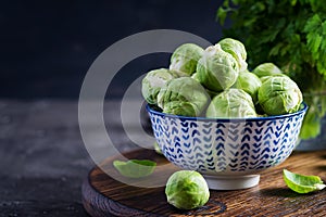 Fresh organic brussels sprouts in a bowl on a dark background.
