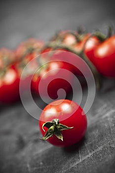 Fresh organic cherry tomatoes bunch closeup on black board