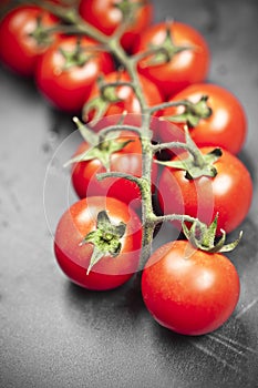 Fresh organic cherry tomatoes bunch closeup on black board