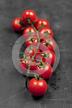 Fresh organic cherry tomatoes bunch closeup on black board