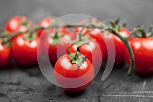 Fresh organic cherry tomatoes bunch closeup on black board