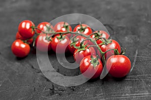 Fresh organic cherry tomatoes bunch closeup on black board