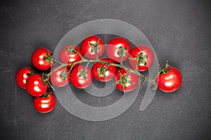 Fresh organic cherry tomatoes bunch closeup on black board background