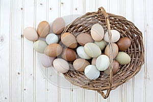 Fresh organic chickeneggs overflow out of basket on wooden backg