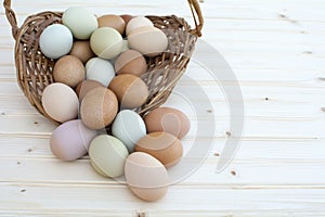 Fresh organic chickeneggs overflow out of basket on wooden backg