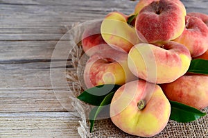 Fresh organic chinese flat peaches with leaves on old wooden background.Saturn donut, Doughnut peach, Paraguayo.Healthy eating or photo