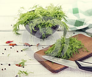 Fresh organic dill on a cutting board and a bunch of dill on a c