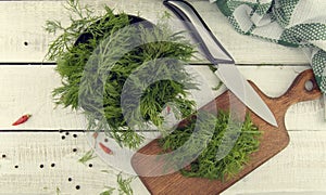 Fresh organic dill on a cutting board and a bunch of dill on a c