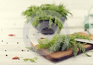 Fresh organic dill on a cutting board and a bunch of dill on a c