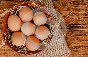 Fresh organic eggs in bowl on wooden rustic background. Directly above, copy space