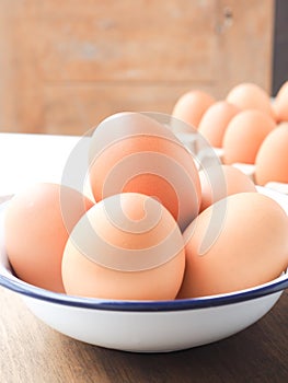 Fresh organic eggs from the farm in a white bowl on wooden background.