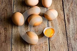 Fresh organic eggs scattered on wood kitchen table, cracked shell with open yolk, soft daylight, baking, Easter concept