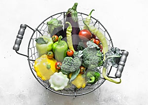 Fresh organic farm vegetables - broccoli, eggplant, pepper, tomatoes, squash in a basket on a light background, top view. Healthy