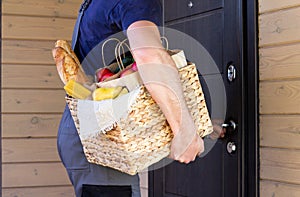 Fresh organic food in a wicker basket in the hands of a bicycle courier. Bike delivery or donation of food concept