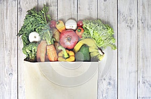 Fresh organic fruits and vegetables top view on wooden table in paper bag. Eco food vegan set. Food delivery