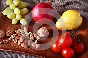 Fresh organic fruits and vegetables on wooden Serving tray. Assorted apple, pear, grapes, tomatoes and nuts.