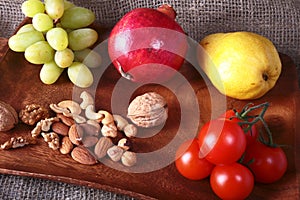Fresh organic fruits and vegetables on wooden Serving tray. Assorted apple, pear, grapes, tomatoes and nuts.