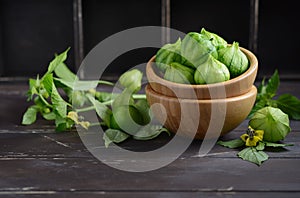 Fresh organic green tomatillos Physalis philadelphica with a husk on rustic wooden table.