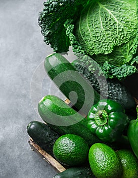 Fresh Organic Green Vegetables Savoy Cabbage Zucchini Cucumbers Bell Peppers Avocados on Black Stone Concrete Background