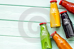 Fresh organic juices in bottles for fitness diet on green wooden background top view mock-up