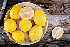 Fresh organic lemons in a colander on a wooden background. Top view