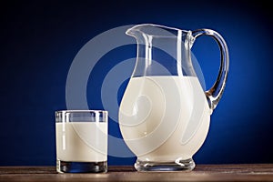 Fresh organic milk in glass jug and glass on wooden table top