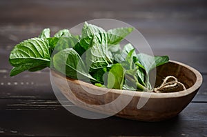 Fresh organic mint bunch in a wooden bowl on the old rustic wooden table.