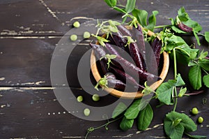 Fresh organic purple green peas in a wooden bowl on rustic wooden table.