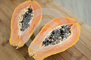 Fresh organic ripe papaya fruit cut in half on a wooden board. Exotic fruits, healthy eating concept